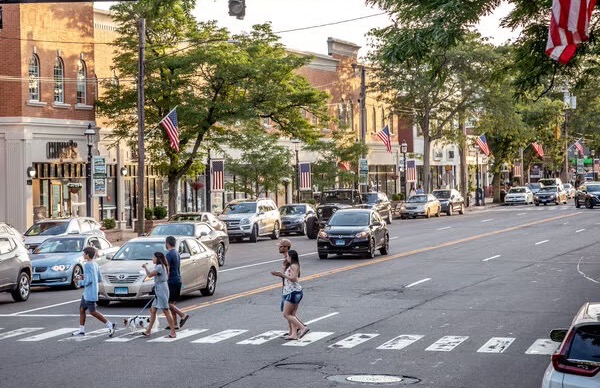 Shops and stationary cars beside a busy pedestrian crossing